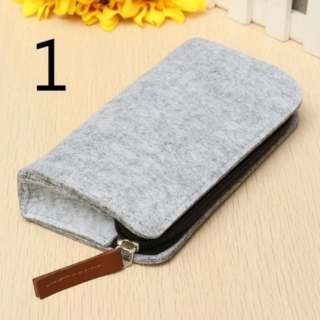 Gray felt pouch with a brown zipper pull on a beige surface with yellow flowers.
