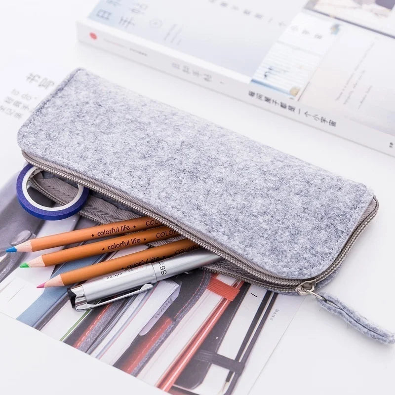 Gray pencil case with stationery items on a newspaper background