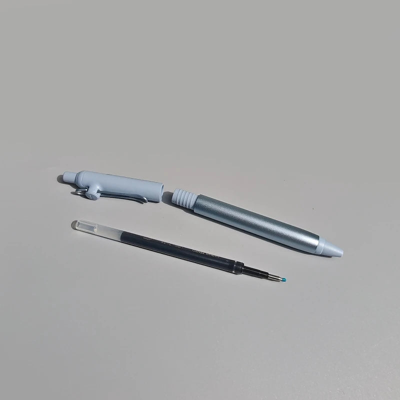 Two pens, one gray and one black with a visible clip, on a light gray background.