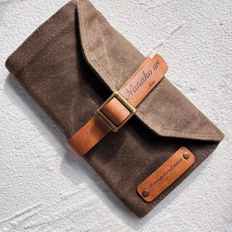 Brown fabric pouch with leather straps and 'Nanako Art' branding on a textured white background