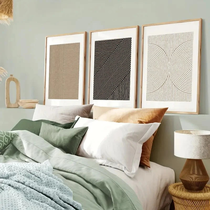 Bedroom with a bed featuring pillows and blankets, framed art on the wall, and a lamp.